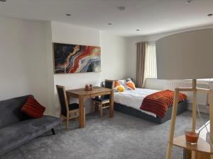 a bedroom with a bed and a table and a couch at Jolly Jupiter at The Moon in Pontnewynydd