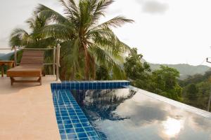 a swimming pool with a bench and a palm tree at Karo Villas in Koh Tao