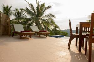 涛岛卡罗别墅的庭院的后面设有两把椅子和棕榈树