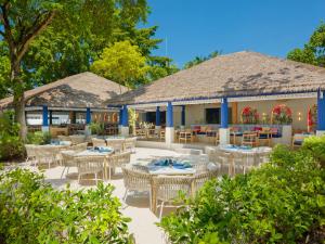 a restaurant with white tables and chairs and trees at Eri Maldives in North Male Atoll