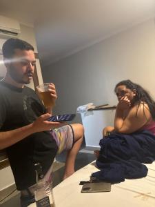 a man and a woman sitting on a bed with a drink at Clt in Brasília