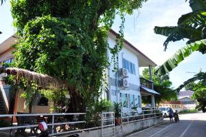 un edificio con un árbol delante de él en The Rim Riverside Guest House en Nong Khai