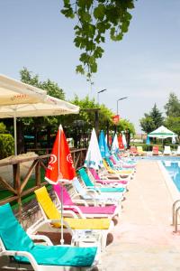 a row of beach chairs with umbrellas next to a pool at Комплекс Тракийски стан in Asenovgrad