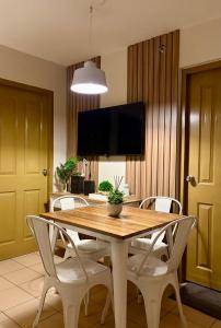 a dining room table with white chairs and a flat screen tv at 8 Spatial Condo in Davao City