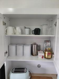 a kitchen shelf filled with dishes and a toaster at Stirling St Surf Villa in Dunedin
