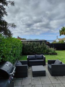 a patio with couches and a table and a grill at Stirling St Surf Villa in Dunedin