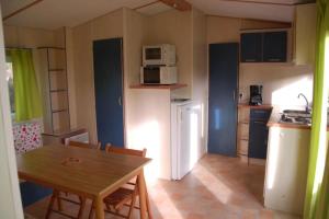 a small kitchen with a table and a microwave at Camping 3 étoiles - Piscine - à 2 minutes des plages in Penvénan