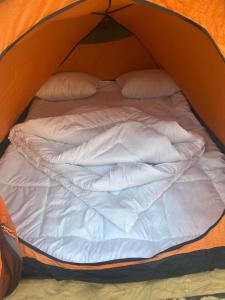 a bed in a tent with white sheets and pillows at مبيت في الصحراء in Tunis