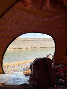 a window in a tent looking out at a body of water at مبيت في الصحراء in Tunis