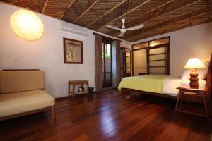 a bedroom with a bed and a couch and a fan at Sala Prabang Hotel in Luang Prabang