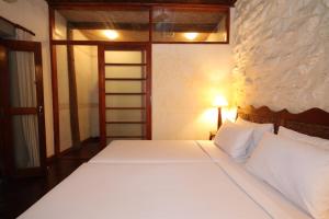 a bedroom with a large bed with white sheets at Sala Prabang Hotel in Luang Prabang