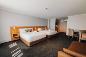 a hotel room with two beds and a desk at Clarion Hotel Townsville in Townsville