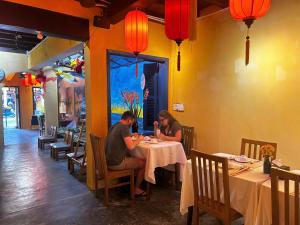 two people sitting at a table in a restaurant at Hoi An Old Town Residence - 56 Phan Boi Chau, Hoi An in Hoi An