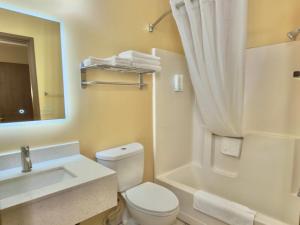 a bathroom with a toilet and a sink and a mirror at Econo Lodge Lansing - Leavenworth in Lansing +17 photos