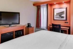 a hotel room with a bed and a flat screen tv at Pittsburgh Airport Inn and Suites in Coraopolis