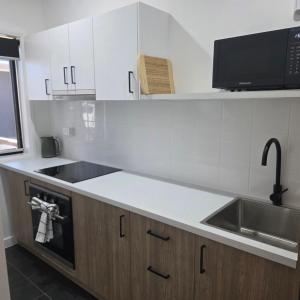 a white kitchen with a sink and a microwave at Heritage City Motor Inn in Broken Hill