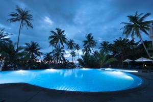 a pool at night with palm trees in the background at Koh Kood Beach Resort in Ko Kood