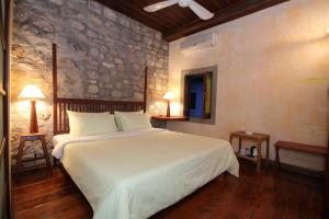 a bedroom with a large white bed and a stone wall at Sala Prabang Hotel in Luang Prabang