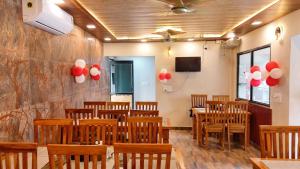 a dining room with wooden chairs and red and white balloons at Corbett Hill Site in Rāmnagar