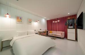 a bedroom with a white bed and a living room at H-AVENUE Hotel Yeongdeungpo in Seoul