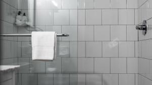 a white tiled bathroom with a towel hanging on a shower at The Sobro Guest House by AvantStay in Nashville