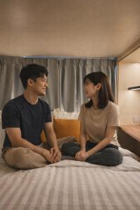 a man and a woman sitting on a bed at Faloe Hostel in Kota Kinabalu