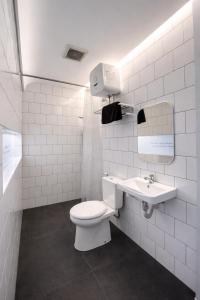 a white bathroom with a toilet and a sink at Turuku in Bandung