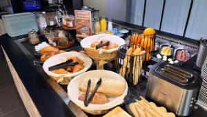 a counter with baskets of bread and baskets of food at Campanile Marmande in Marmande