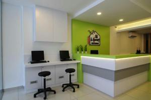 a kitchen with a counter with two stools and green walls at i-homey guesthouse in Alor Setar