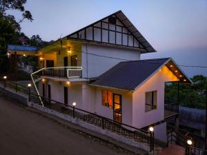 a white house with a black roof at night at Rock And Mist Munnar House Resort in Munnar