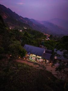 a view of a building on a hill at night at Rock And Mist Munnar House Resort in Munnar