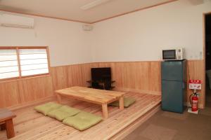 een woonkamer met een tafel en een koelkast bij Simple Sleep 個室カプセル in Hitoyoshi