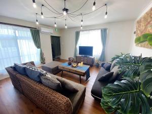 a living room with a couch and a tv at 外人住宅ーアメリカンビレッジ車20分 in Urazoe