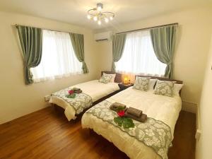 a bedroom with two beds and two windows at 外人住宅ーアメリカンビレッジ車20分 in Urazoe