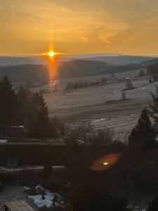a sunset over a field with the sun in the distance at Ferienzimmer Schürer in Lauter +2 photos