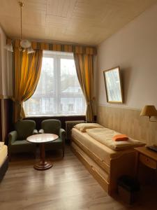 a bedroom with a bed and a chair and a window at Hotel U Branky in Stříbro