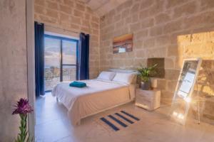 a bedroom with a bed and a large window at Fiftyfour West Boutique Living in Għarb +114 photos