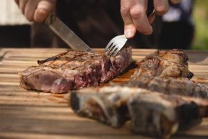 a person cutting a steak with a fork and knife at Wild Agriturismo Podere della Bruciata in Chiusi +29 photos