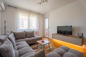 a living room with a couch and a flat screen tv at HM Apartments in Inđija