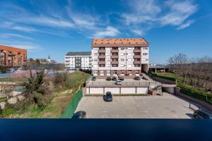 a building with a red roof with a parking lot at HM Apartments in Inđija