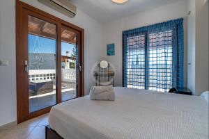 a bedroom with a large bed and a balcony at Villa Rania - Porto Hydra in Ermioni