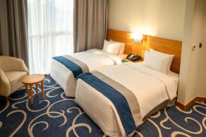 a hotel room with two beds and a chair at Reya Creek Hotel in Dubai +68 photos