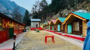 a row of colorful buildings with a red stool at Mahi camping & cottages in Jagatsukh
