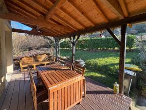 a wooden deck with a table and chairs on it at Logis Fontaines in Champagnat