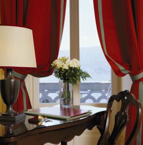 eine Vase aus Blumen auf einem Tisch mit einem Fenster in der Unterkunft Grand Hotel Majestic in Verbania