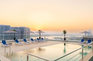 a pool on the roof of a building with chairs and umbrellas at Reya Creek Hotel in Dubai