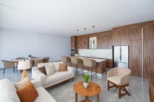 a living room with a white couch and a kitchen at Arch View Luxury Condo with Heated Rooftop Pool and Jacuzzi in Cabo San Lucas