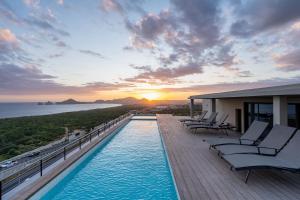 a pool on a building with chairs and the sunset at Arch View Luxury Condo with Heated Rooftop Pool and Jacuzzi in Cabo San Lucas