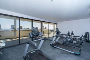 a gym with three cardio machines in a room with windows at Arch View Luxury Condo with Heated Rooftop Pool and Jacuzzi in Cabo San Lucas