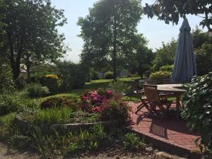 a patio with a table and an umbrella and flowers at Demeure Saint Gildas in La Haye-Pesnel